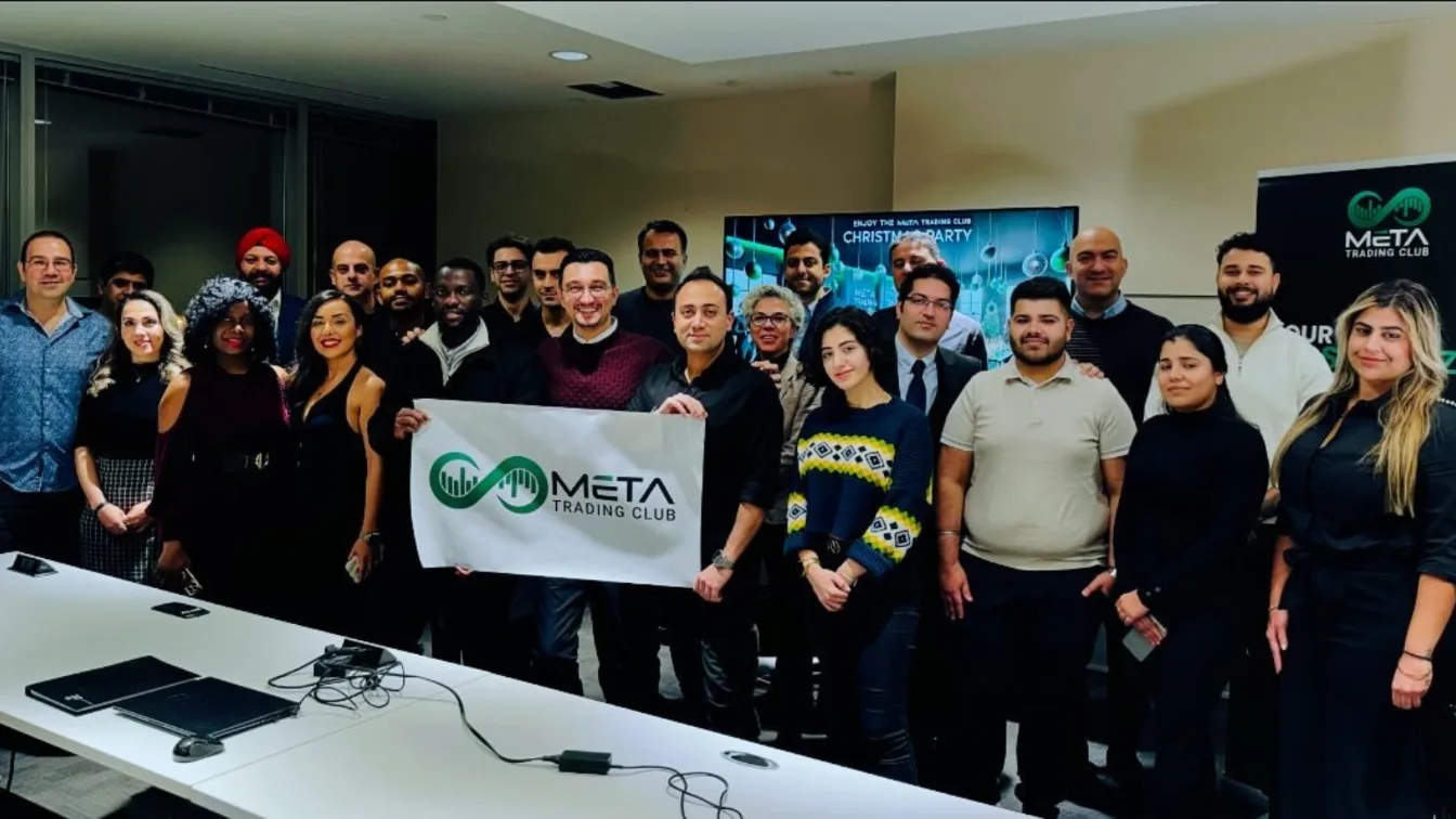 Large group of Meta Trading Club members holding the club banner in a Toronto boardroom