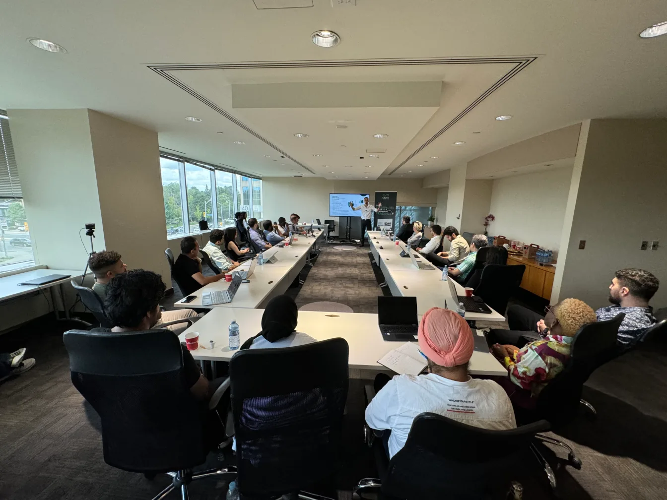 Wide view of a long boardroom filled with attendees at a Meta Trading Club event